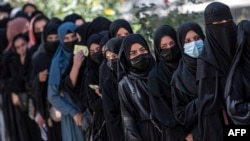 FILE - Female Afghan students stand in a queue after they arrive for entrance exams at Kabul University in Kabul on Oct. 13, 2022. After the hardline Taliban regained power in Afghanistan, they banned girls’ education past the sixth grade.