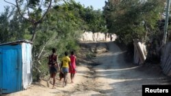 Girls carry roosters down a dirt road in Jean-Rabel, Haiti, Jan. 31, 2020. 