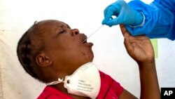 FILE: A heath worker collects a sample from a woman for coronavirus testing during the screening and testing campaign. (AP Photo/Themba Hadebe)