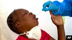 A heath worker collects a sample from a woman for coronavirus testing during the screening and testing campaign aimed to combat the spread of COVID-19, in Diepsloot, north of Johannesburg, South Africa, Friday, May 8, 2020. (AP Photo/Themba Hadebe)