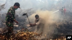 Warga dan tentara berupaya memadamkan kebakaran di sebuah lahan di Rimbo Panjang, Riau, September 2015. 