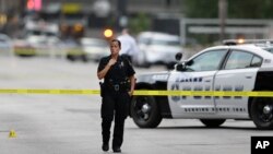 A Dallas police officer guards the scene of last night's shooting as investigators work in downtown Dallas on July 8, 2016. 