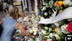 FILE - Mourners bring flowers to a makeshift memorial, Aug. 6, 2019, for the slain and injured in the Oregon District after a mass shooting in Dayton, Ohio, Aug. 4, 2019.