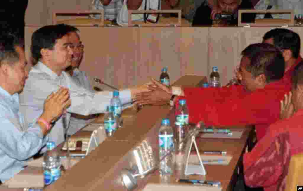 Thai Prime Minister Abhisit Vejjajiva (L) shakes hands with Red-Shirt demonstration leader Veera Musikapong (R) during meeting in Bangkok on March 28, 2010.