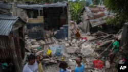 Una familia desayuna frente a casas destruidas por un terremoto de magnitud 7.2 en Les Cayes, Haití, el domingo 15 de agosto de 2021.