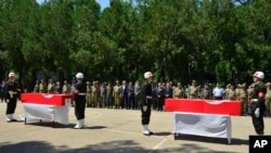 Turkish soldiers, army officers and officials stand at attention next to the coffins of soldiers Mehmet Kocak and Ismail Yavuz, during a ceremony in Diyarbakir, Turkey, Sunday, July 26, 2015.