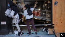 People exit damaged stores after the glass was knocked out in the Chelsea neighborhood of New York, Monday, June 1, 2020. (AP Photo/Craig Ruttle)