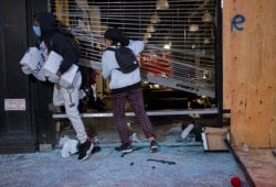 People exit damaged stores after the glass was knocked out in the Chelsea neighborhood of New York, June 1, 2020.