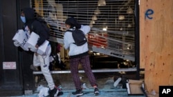 People exit damaged stores after the glass was knocked out in the Chelsea neighborhood of New York, Monday, June 1, 2020. (AP Photo/Craig Ruttle)