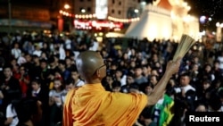 A buddhist monk sprinkles holy water as people pray for victims who died in a mass shooting involving a disgruntled Thai soldier on a shooting rampage, in Nakhon Ratchasima, Thailand, Feb. 9, 2020.