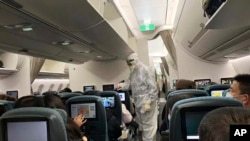 FILE - A worker in a hazardous materials suit takes the temperature of a passenger on a Cathay Pacific flight from Hong Kong to Rome after it landed at Rome Fiumicino Airport in Rome, Italy, Jan. 31, 2020.