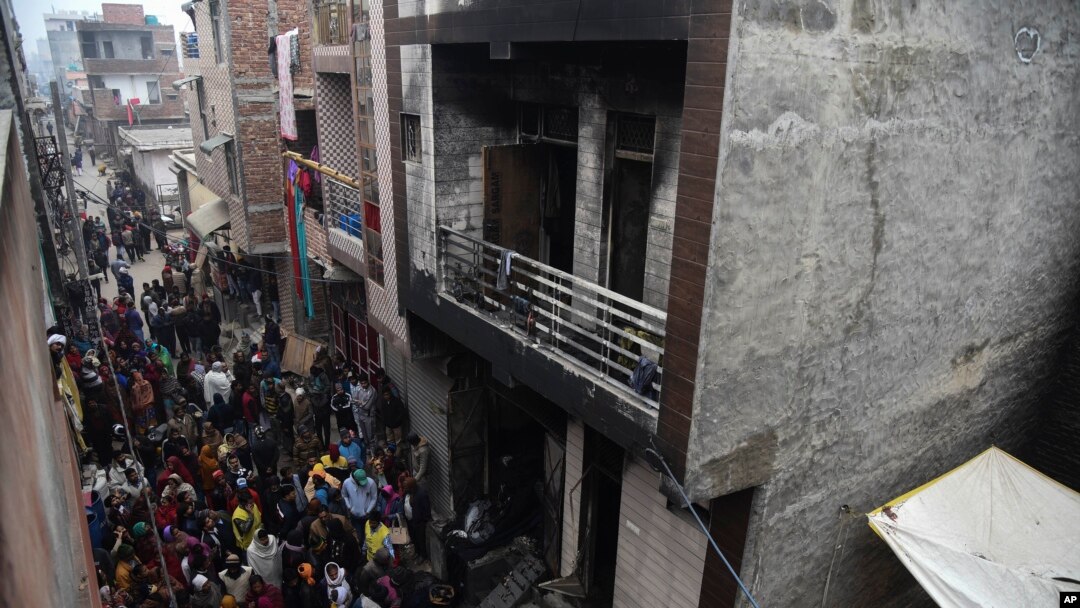 Warga berkumpul di sekitar gudang tempat terjadinya kebakaran pada dini hari Senin, 23 Desember 2019 di daerah Kirari, New Delhi, India.