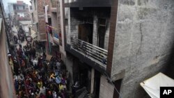 People gather around a warehouse where a fire broke out in the early hours of Monday at Kirari area of New Delhi, India, Monday, Dec.23, 2019. The blaze killed 9 people and left at least 3 injured, a fire official said.