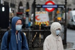 Pedestrians wear face masks as they walk at Piccadilly Circus main tourist destination in central London, as the public are asked to take precautions to protect themselves from the COVID-19 Coronavirus outbreak, March 5, 2020.