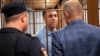 French citizen Laurent Vinatier, center, stands in a defendant's cage speaking with his lawyer as a court convicted him of collecting military information, at the Zamoskvoretsky District Court in Moscow, Russia, Oct. 14, 2024.