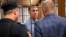 French citizen Laurent Vinatier, center, stands in a defendant's cage speaking with his lawyer as a court convicted him of collecting military information, at the Zamoskvoretsky District Court in Moscow, Russia, Oct. 14, 2024.
