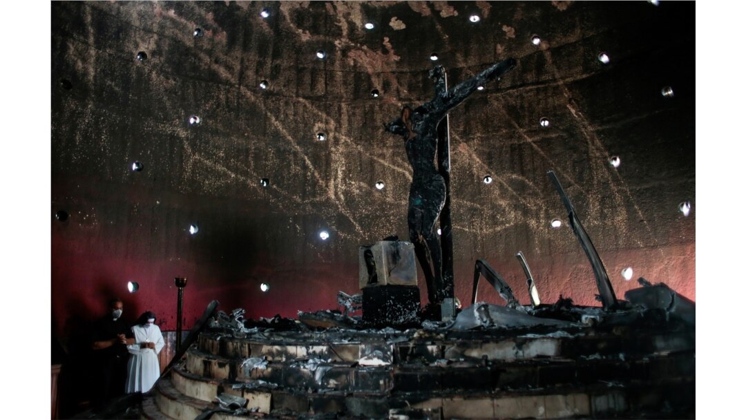 Un sacerdote y una religiosa rezan frente al crucifijo Sangre de Cristo, el domingo 2 de agosto, después que la capilla donde se encuentra en la catedral de Managua fuera destruida por un incendio, el viernes 31 de julio de 2020.