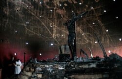 Un sacerdote y una religiosa rezan frente al crucifijo Sangre de Cristo, el domingo 2 de agosto, después que la capilla donde se encuentra en la catedral de Managua fuera destruida por un incendio, el viernes 31 de julio de 2020.