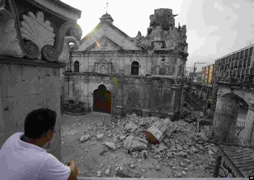 A resident looks at the rubble following an earthquake that hit Cebu city and toppled a church's bell tower, Philippines, Oct. 15, 2013.