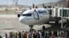 Afghan people climb atop a plane as they wait at the Kabul airport in Kabul on August 16, 2021, after a stunningly swift end to Afghanistan's 20-year war, as thousands of people mobbed the city's airport trying to flee the group's feared hardline brand of