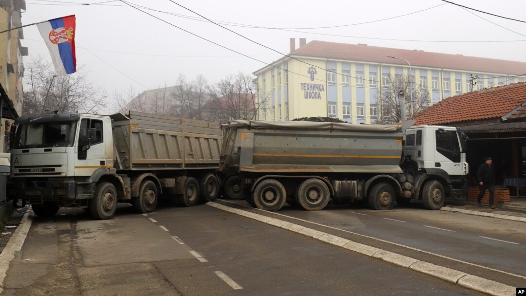 A man passes by a barricade made of trucks loaded with stones that was erected during the night on a street in northern, Serb-dominated part of ethnically divided town of Mitrovica, Kosovo, Dec. 27, 2022.