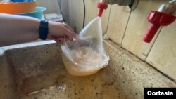 Una ciudadana agarra agua de un grifo de su casa en Maracaibo, estado Zulia, Venezuela. Junio, 2020. Foto: Gustavo Ocando - VOA.