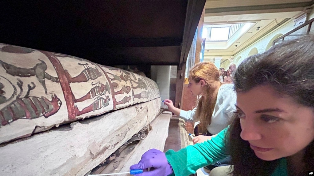 In this undated photo, Emma Paolin, PhD researcher at University of Ljubljana, background and Dr. Cecilia Bembibre, lecturer at the University College London take swab samples for the purpose of analysis at the Krakow University of Economics. (Abdelrazek Elnaggar via AP)