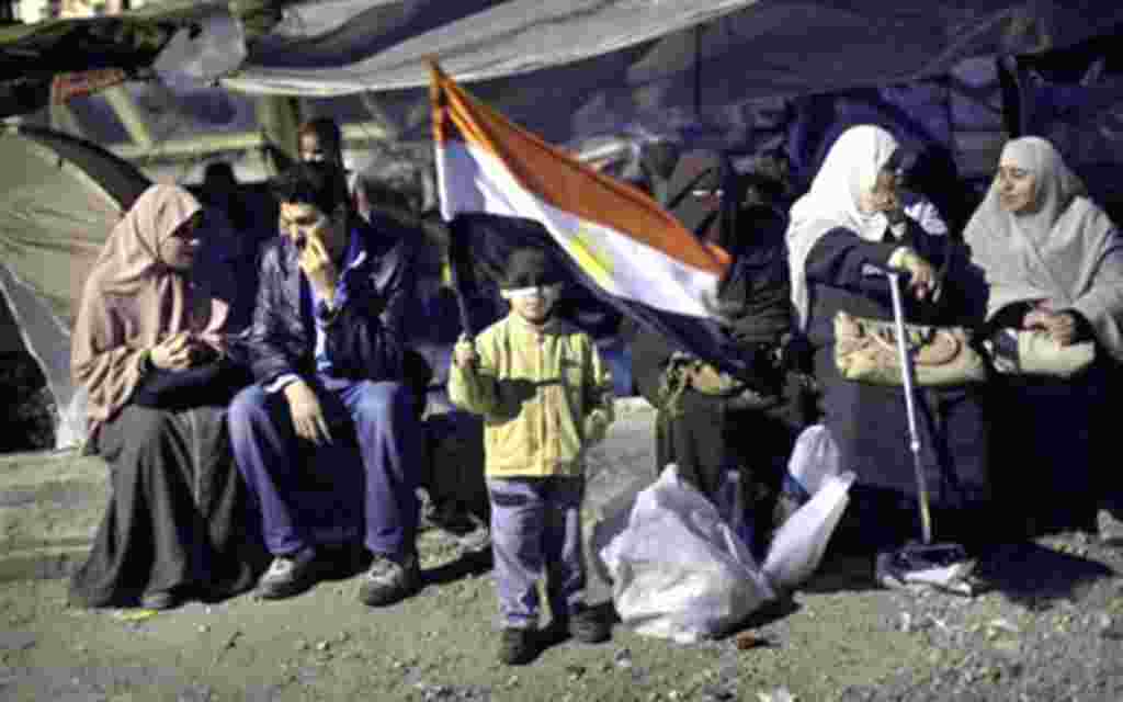 A boy holds an Egyptian flag next to anti-Mubarak protesters at Tahrir Square in Cairo, Egypt, February 6, 2011