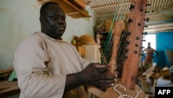 Frère Marie Firmin, 40 ans, joue de la kora à l'intérieur de l'atelier de fabrication de kora de l'abbaye de Keur Moussa, au Sénégal, le 19 mai 2021.