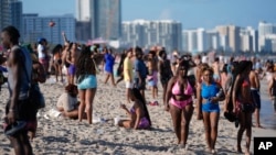 ARCHIVO - Turistas y residentes de Miami Beach caminan por la playa el viernes 15 de marzo de 2024, en medio de las vacaciones de primavera.