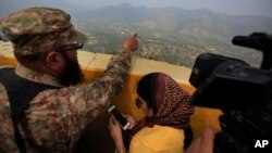 FILE - A Pakistan army officer points out the Indian forward area posts to journalists at Bagsar post on the Line of Control that divides Kashmir between Pakistan and India, Oct. 1, 2016. 