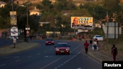 Residents wait for taxi transport beneath election posters in Pietermaritzburg in South Africa's KwaZulu Nataal province, April 29, 2014. 