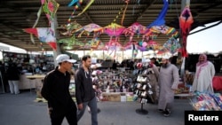 FILE - Visitors walk in front of a stands during weekend flea market in Isa Town, Bahrain, Feb. 10, 2018. In a report published Jan. 14, 2019, a group of Middle East researchers found that areas where residents are exposed to sectarian mixing are less prone to sectarian violence.