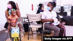 NEW ORLEANS, LOUISIANA - AUGUST 12: LaToya Feltus (L) sits with her daughters Taraji Phillips (L) and Amya Feltus, 13, after both LaToya and Amya received a COVID-19 vaccination dose at a clinic operated by DePaul Community Health Center on August…
