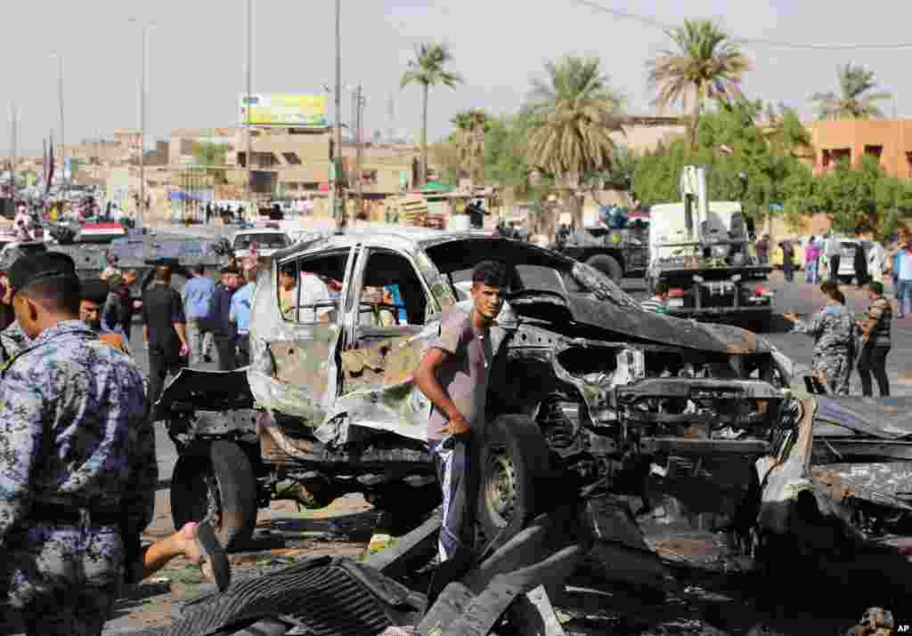 Civilians and security forces inspect the site of a car bomb explosion in the southeastern neighborhood of New Baghdad, Iraq, Sept. 10, 2014.