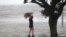 A woman stands on a partially submerged picnic bench in the storm surge from Isaac, on Lakeshore Drive along Lake Pontchartrain, as the storm approaches landfall, in New Orleans, Aug. 28, 2012. 