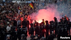 Riot policemen stand guard as the right-wing supporters protest after a German man was stabbed last weekend in Chemnitz, Germany, Aug. 27, 2018.