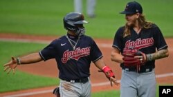 FILE - Cleveland Indians' Francisco Lindor, left, talks with starting pitcher Mike Clevinger during a simulated baseball game at Progressive Field, July 10, 2020, in Cleveland. 