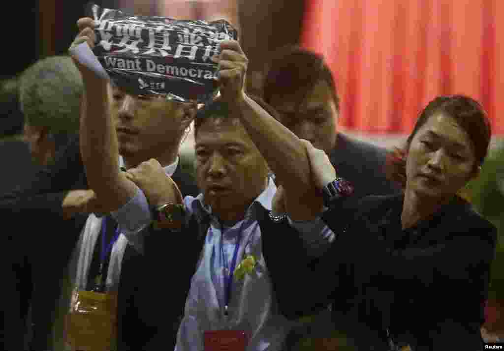 Pro-democracy lawmaker Wu Chi-wai (C) from the Democratic Party is grabbed by security guards as he protests against Li Fei, Hong Kong Sept. 1, 2014