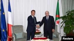 FILE—French President Emmanuel Macron shakes hand with Algerian President Abdelmadjid Tebboune, in Algiers, Algeria, August 25, 2022.