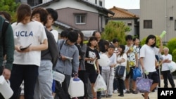 Warga antre untuk mendapatkan air minum di sebuah sekolah dasar di Takatsuki, Osaka, 18 Juni 2018, setelah gempa kuat mengguncang wilayah itu pada jam sibuk di pagi hari
