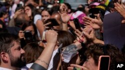 El presidente chileno Gabriel Boric toma la mano de un seguidor mientras saluda a una multitud frente al palacio presidencial de La Moneda reunida para celebrar su primer aniversario en el cargo en Santiago, Chile, el 11 de marzo de 2023.