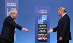 FILE - British Prime Minister Boris Johnson, left, reaches out to shake hands with U.S. President Donald Trump at the official arrivals for a NATO leaders meeting at The Grove hotel and resort in Watford, Hertfordshire, England, Dec. 4, 2019.