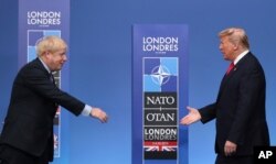 FILE - British Prime Minister Boris Johnson, left, reaches out to shake hands with U.S. President Donald Trump at the official arrivals for a NATO leaders meeting at The Grove hotel and resort in Watford, Hertfordshire, England, Dec. 4, 2019.