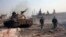 Forces loyal to Syria's President Bashar al-Assad hold their weapon as they stand near a tank inTel Hasel, Aleppo province after capturing it from rebels, Nov. 15, 2013. 
