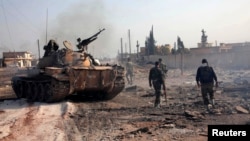 Forces loyal to Syria's President Bashar al-Assad hold their weapon as they stand near a tank inTel Hasel, Aleppo province after capturing it from rebels, Nov. 15, 2013. 