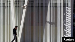 ARCHIVO - Una persona camina junto a un edificio de Telefónica, en Barcelona, España.