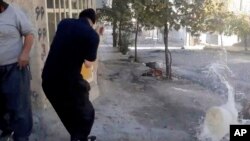 In this image from video provided by Hengaw Organization for Human Rights, a protester reacts after a water container was hit by a bullet during a protest in Javanrud, a Kurdish town in western Iran, Nov. 21, 2022.