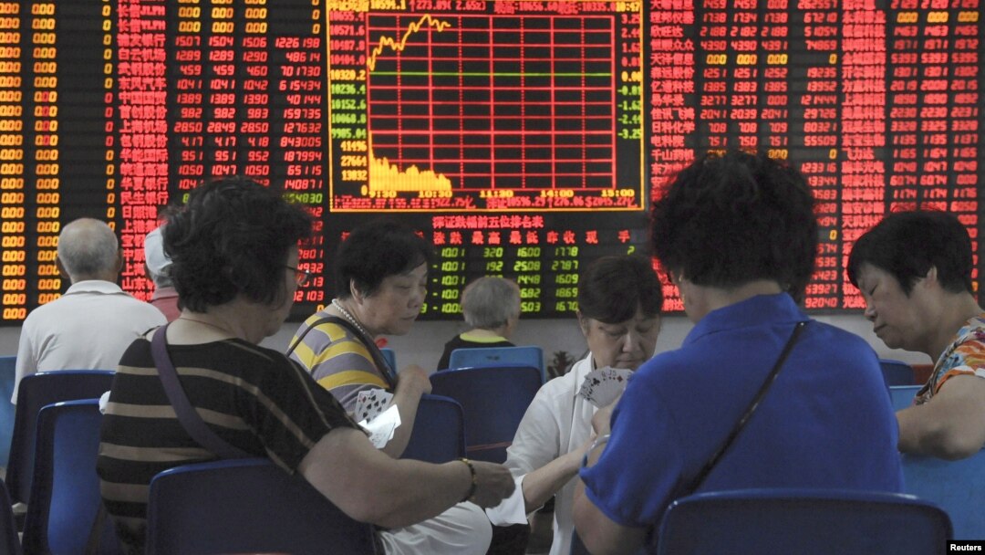 Para investor China bermain kartu di depan layar informasi bursa saham di Shanghai, China, Rabu (9/9).
