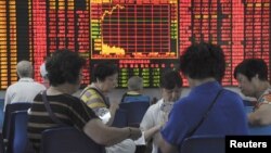 Para investor China bermain kartu di depan layar informasi bursa saham di Shanghai, China, Rabu (9/9).